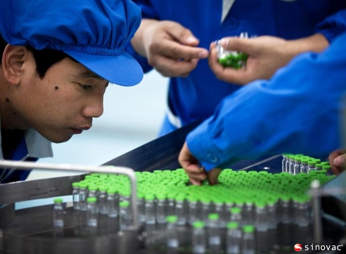 workers inspect labels on vials containing H5N1 flu vaccine during production at the Beijing-based drug maker Sinovac Biotech Ltd. in Beijing